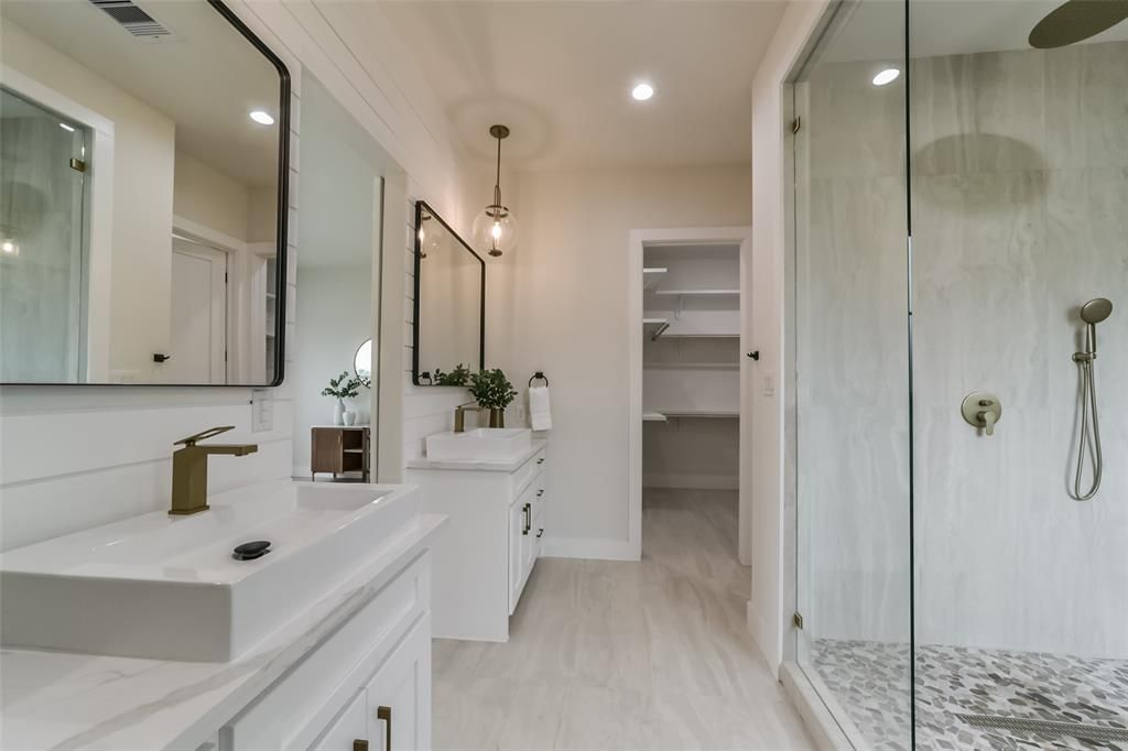 A bathroom with two sinks and a walk in shower