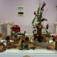 Decorative floral arrangements on a table against a pale purple wall