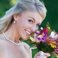 Smiling woman with short blonde hair holding a colorful bouquet outdoors