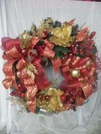 Red and gold decorative holiday wreath with ribbons and ornaments on a white background