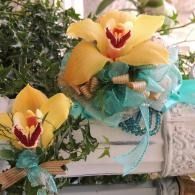Yellow orchid flowers with teal ribbon bows arranged in a decorative floral display