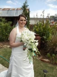 Bride in a white dress holding a bouquet outdoors in a garden