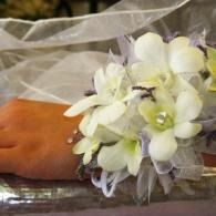 White flower corsage on a wrist, resting on a clear plastic surface