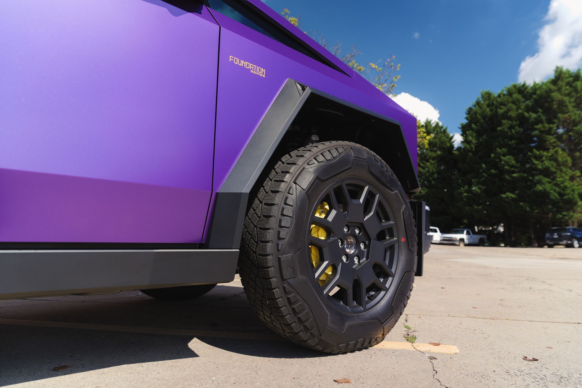 A purple and green tesla cybertruck is parked in a parking lot.