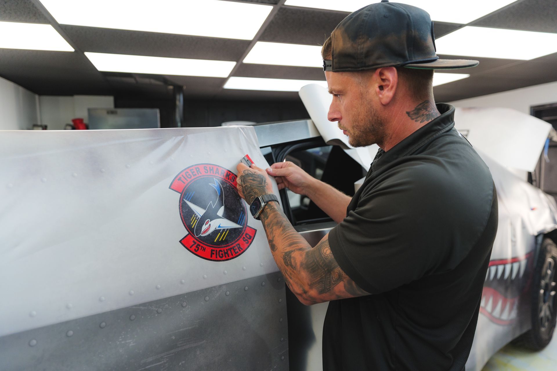 A person wearing black gloves is polishing the hood of a car.