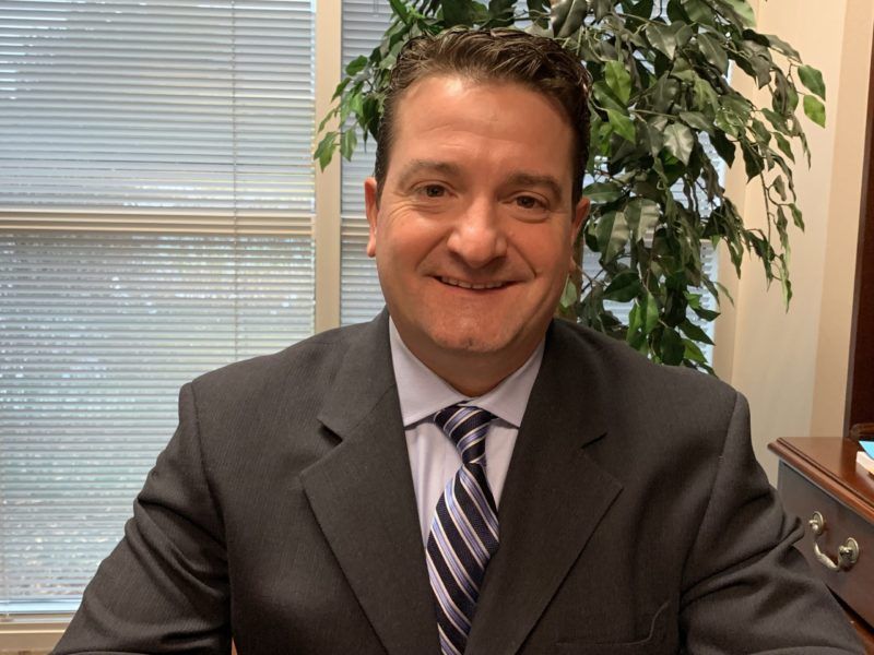 A smiling doctor in a lab coat with a stethoscope around his neck.