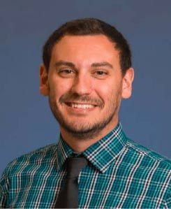 A smiling doctor in a lab coat with a stethoscope around his neck.