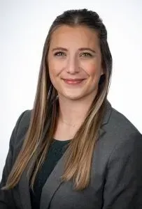 A smiling doctor in a lab coat with a stethoscope around his neck.
