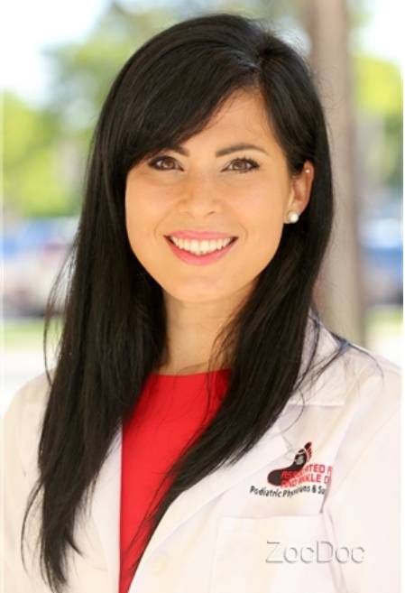 A smiling doctor in a lab coat with a stethoscope around his neck.