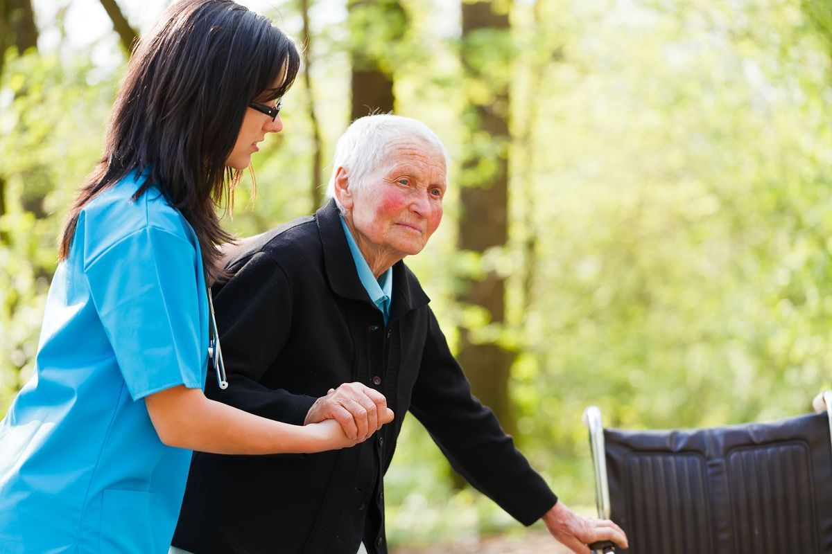 A nurse is helping an elderly woman in a wheelchair