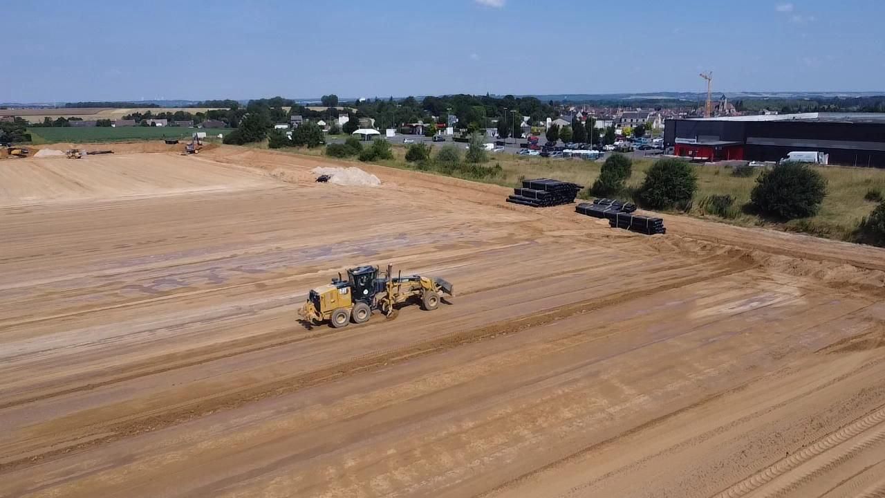 Une vue aérienne d'un chantier de construction avec beaucoup de terre et de camions.