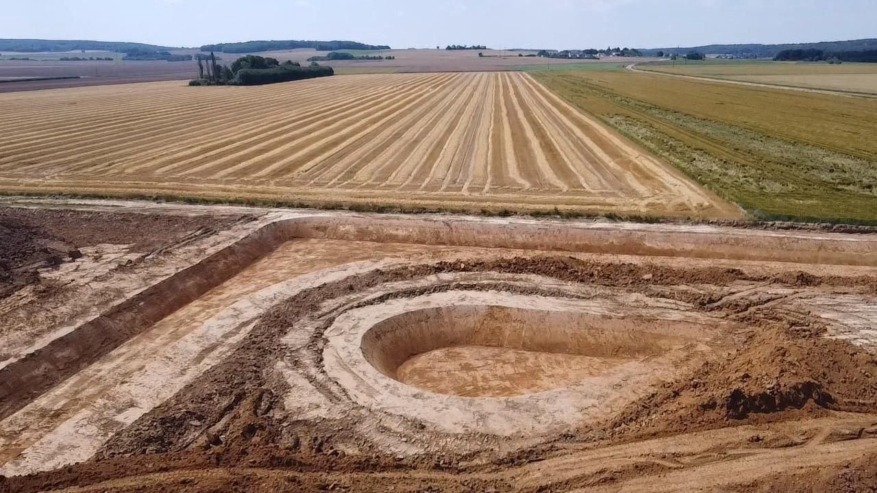 Une vue aérienne d'un champ de terre avec un grand trou au milieu.
