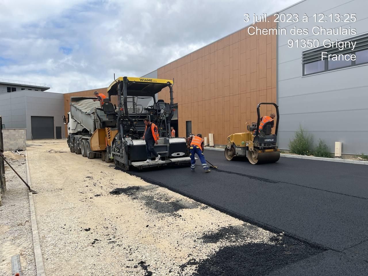 Un groupe de personnes travaille sur une route devant un immeuble.