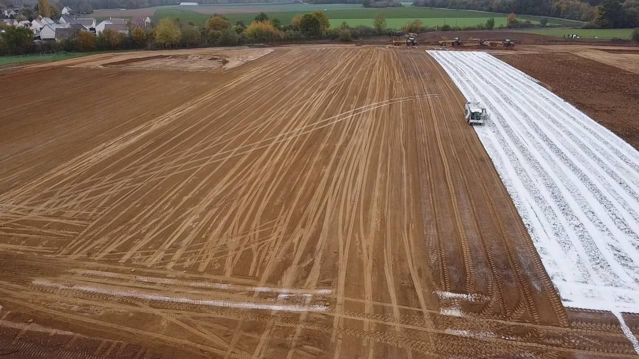 Une vue aérienne d'un champ de terre recouvert d'une bâche blanche.