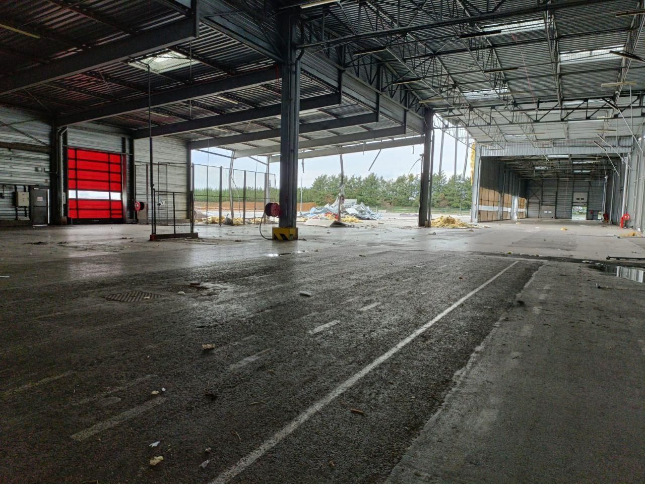 Un grand entrepôt vide avec une porte rouge et un sol en béton.