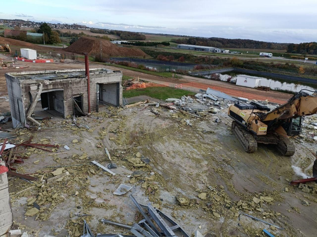 Une vue aérienne d'un bâtiment en cours de démolition avec un bulldozer.