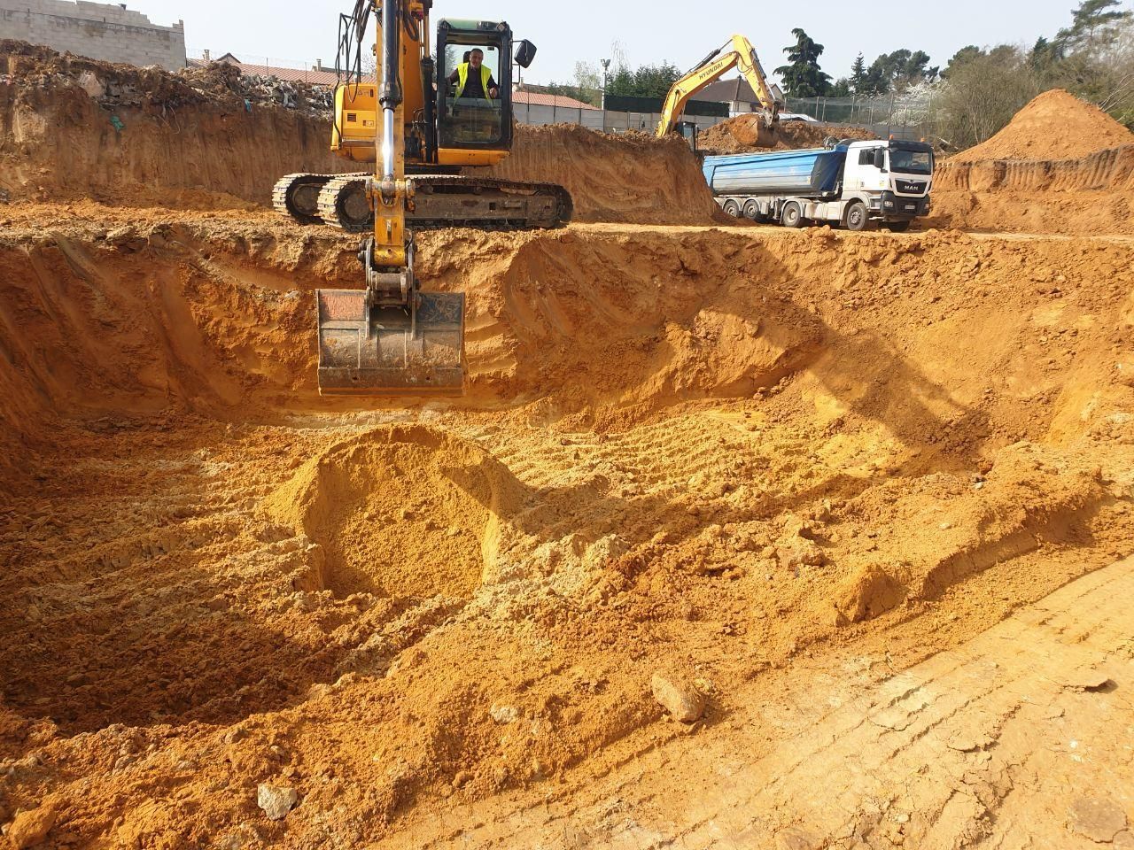 Une excavatrice jaune creuse un trou dans la terre.