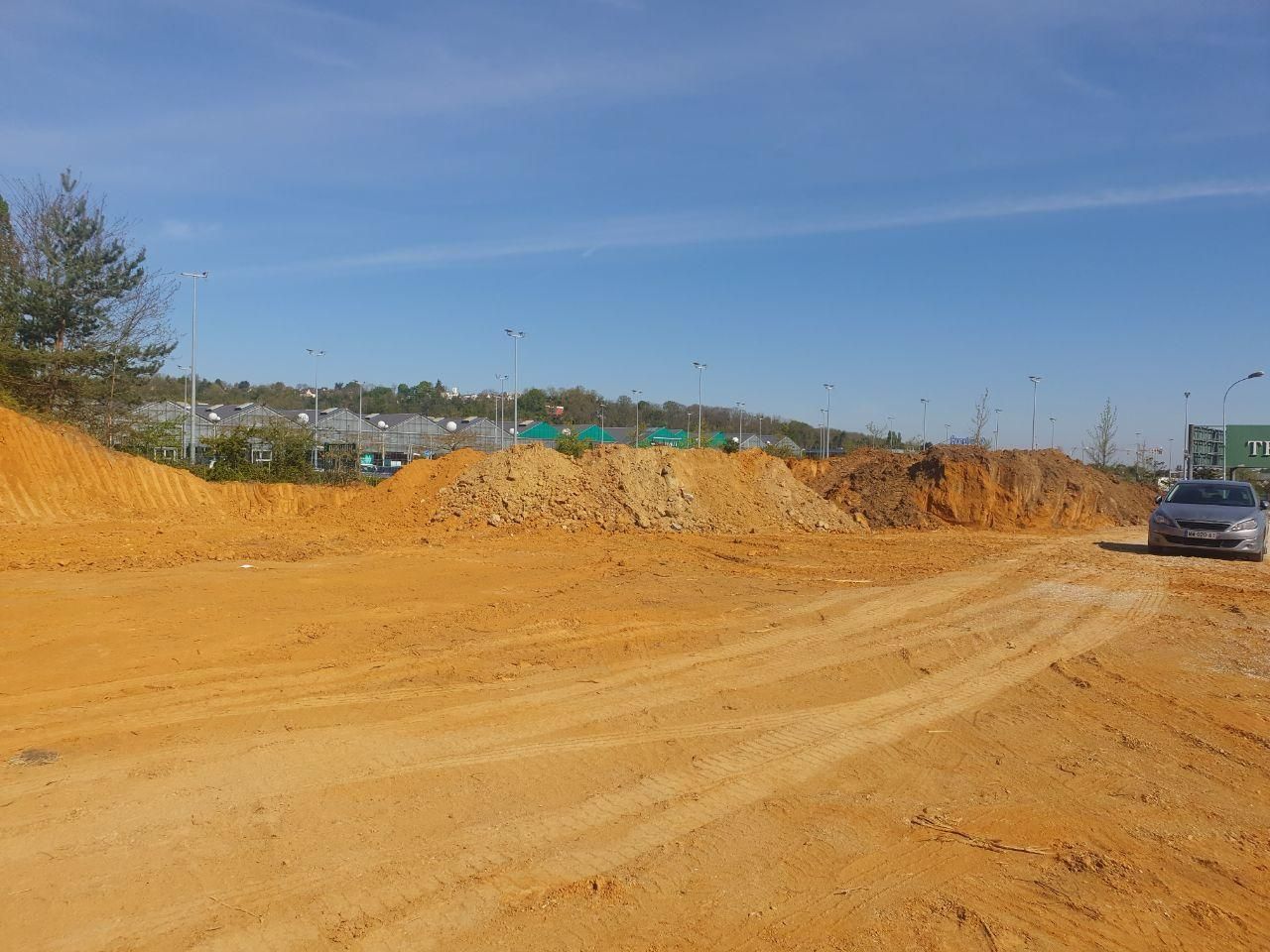 Une voiture roule sur un chemin de terre à côté d'un tas de terre.