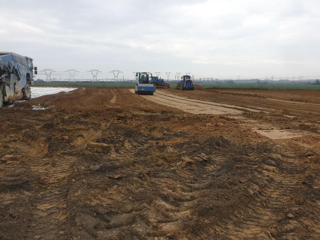 Un groupe de tracteurs travaillent sur un chemin de terre dans un champ.