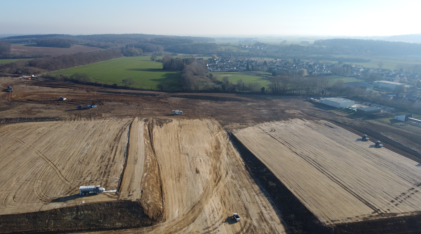 Une vue aérienne d'un grand champ de terre avec une ville en arrière-plan.
