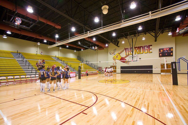 a group of girls are standing on a volleyball court in a gym .