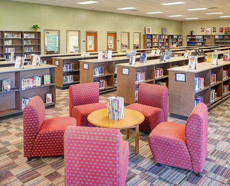a library filled with books and chairs and a table