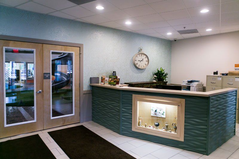 a hotel lobby with a green counter and a clock on the wall .