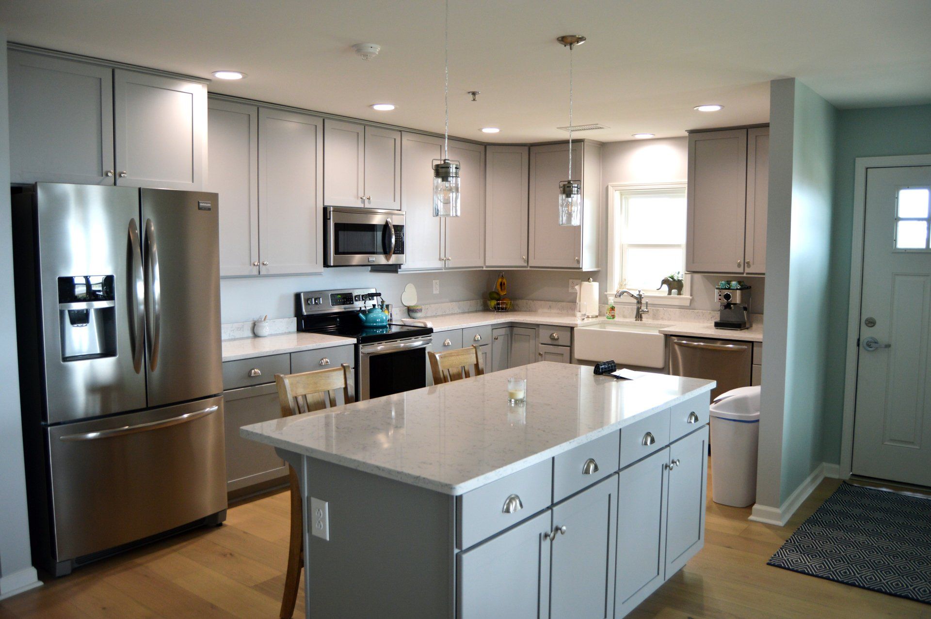 a kitchen with white cabinets , stainless steel appliances , and a large island in the middle .