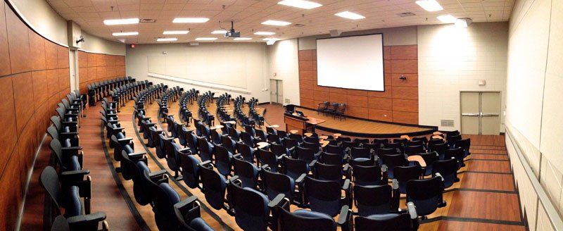 an auditorium with rows of chairs and a projector screen