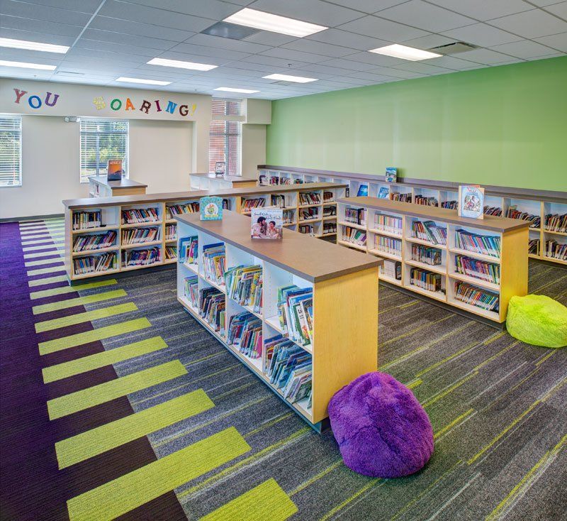 a library with a purple bean bag chair in the middle of the room .
