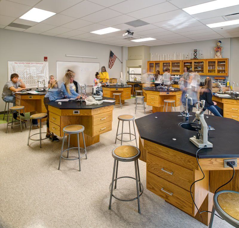 a group of people are sitting at desks in a classroom