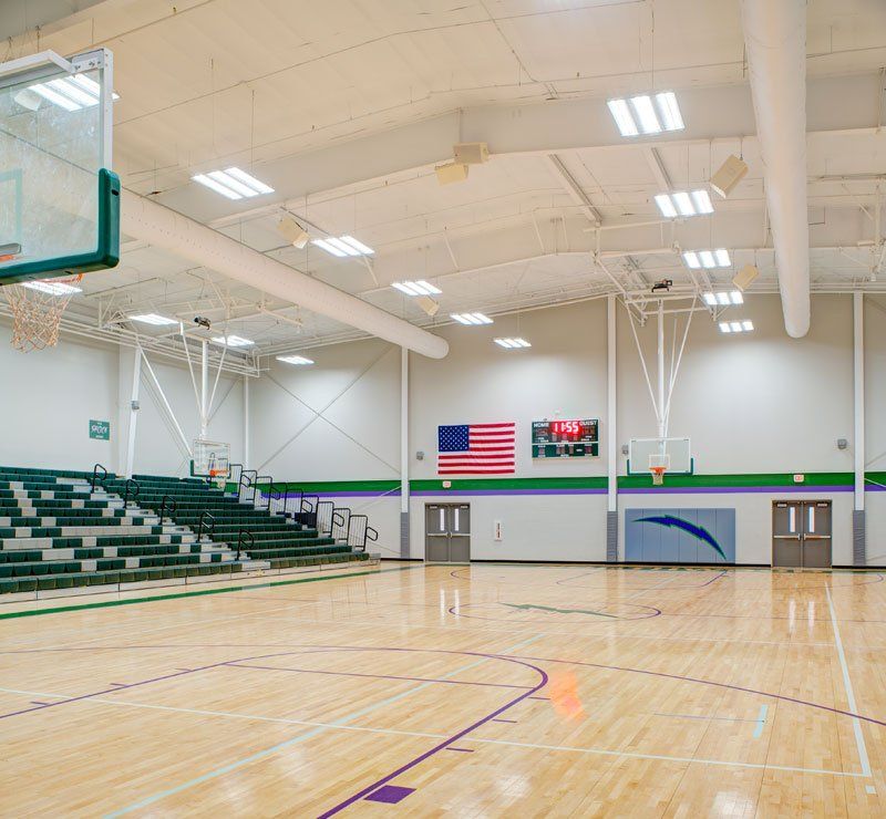 a large indoor basketball court with bleachers and a basketball hoop .