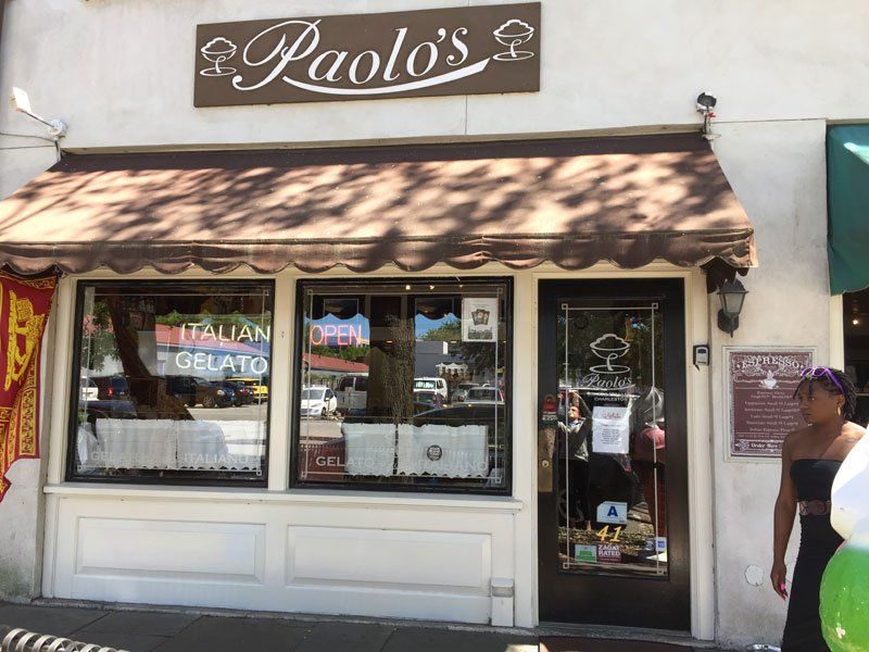 a woman is walking past a paolo 's italian gelato shop