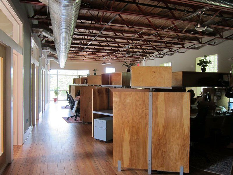 a large office with wooden cubicles and a ceiling fan