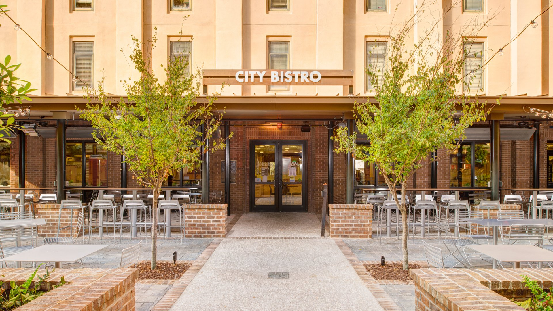 the entrance to the city bistro restaurant is surrounded by trees and tables .