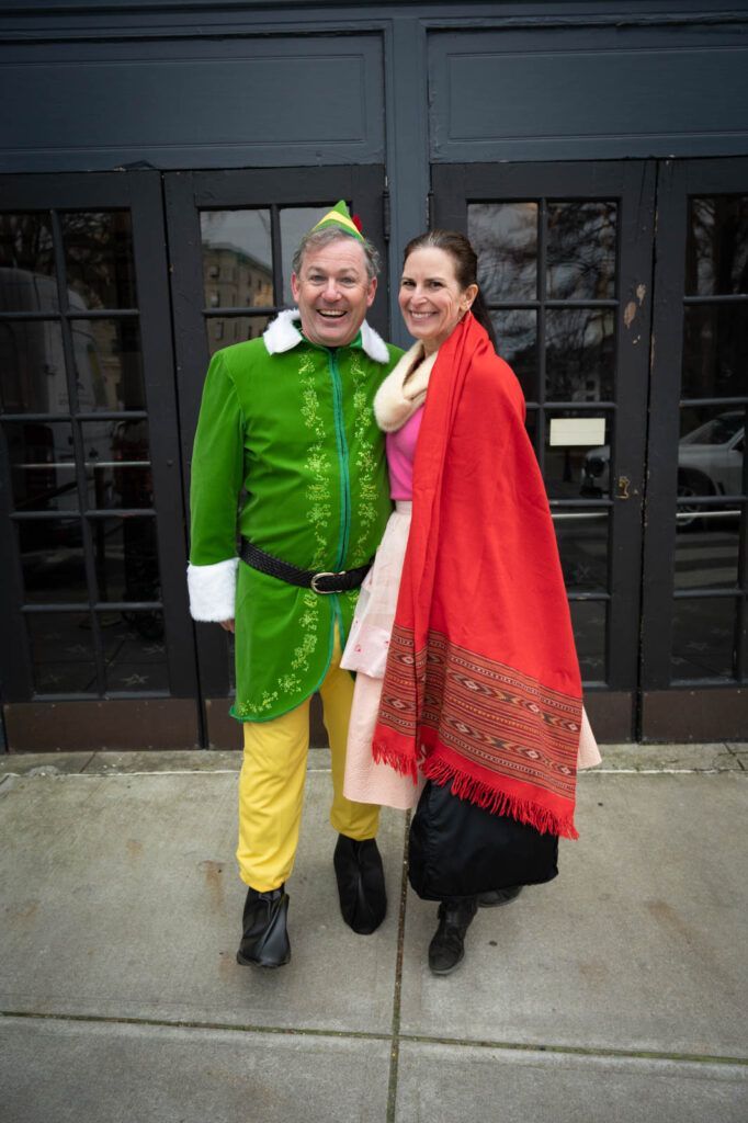 A picture of Kurt Edenbach, owner of Memorial Funeral Home, in front of the Jane Pickens Theater with his wife Meghan, dressed as an elf as well. 