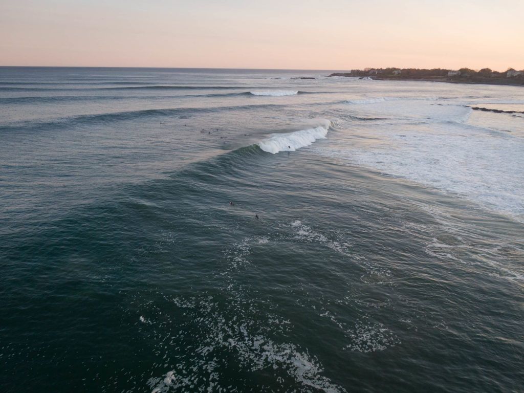 an aerial view of a surfer riding a wave in the ocean at sunset .