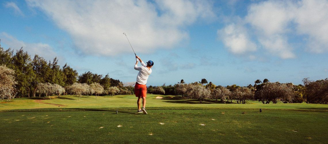 A man is swinging a golf club on a golf course.