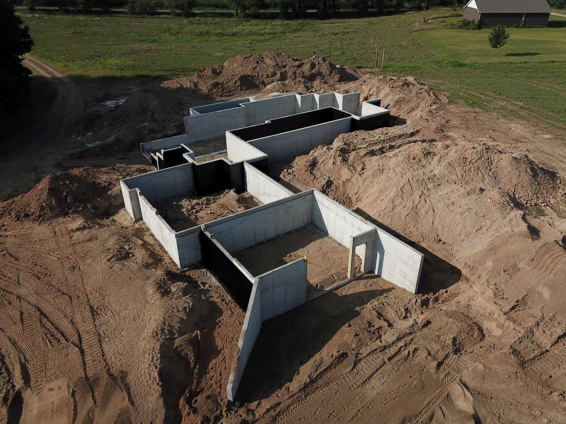 An aerial view of a concrete foundation for a new house under construction on a dirt lot.