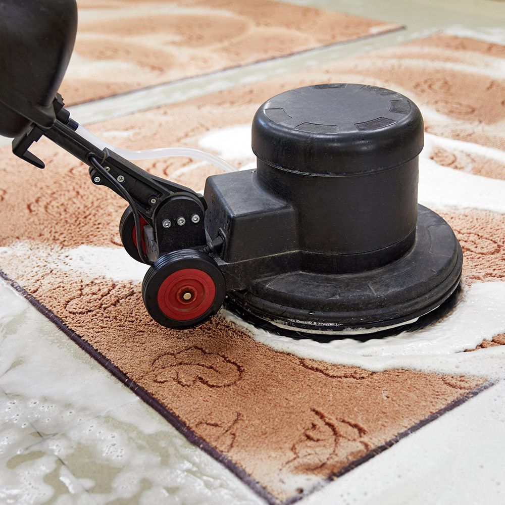 A person is cleaning a rug with a machine.