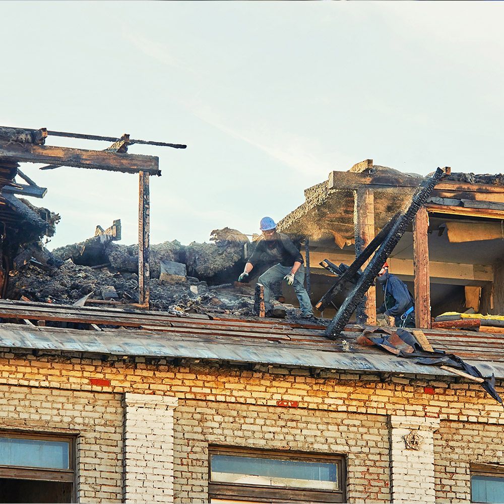 A man is working on the roof of a brick building