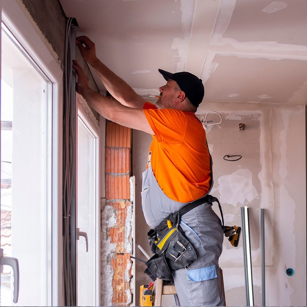 A man is working on a window in a room.