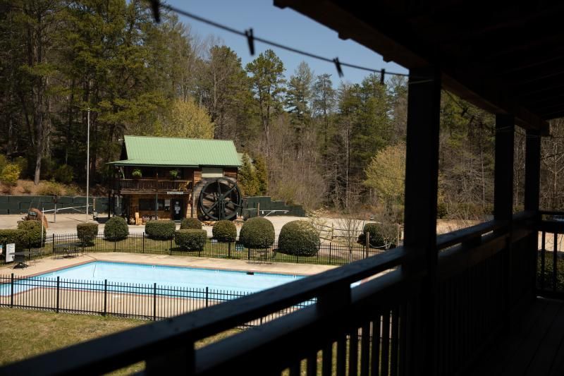 Covered porch overlooking a pool and landscaped yard with a small green-roofed pavilion