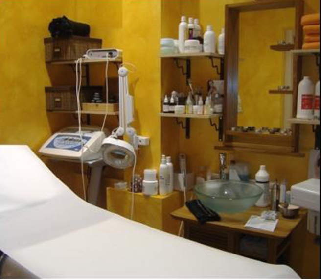 Sala trattamenti spa con pareti gialle, lettino per massaggi e prodotti per la cura della pelle.