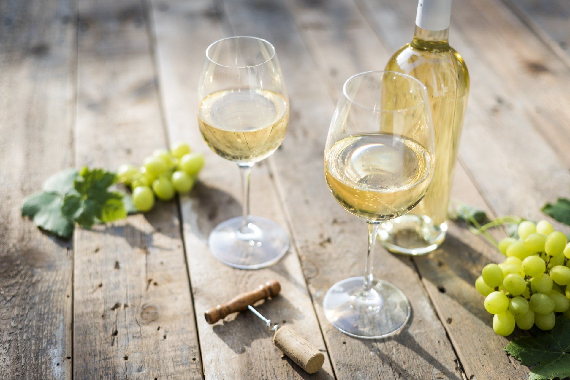 2 Weingläser mit Weißwein auf einem Holztisch