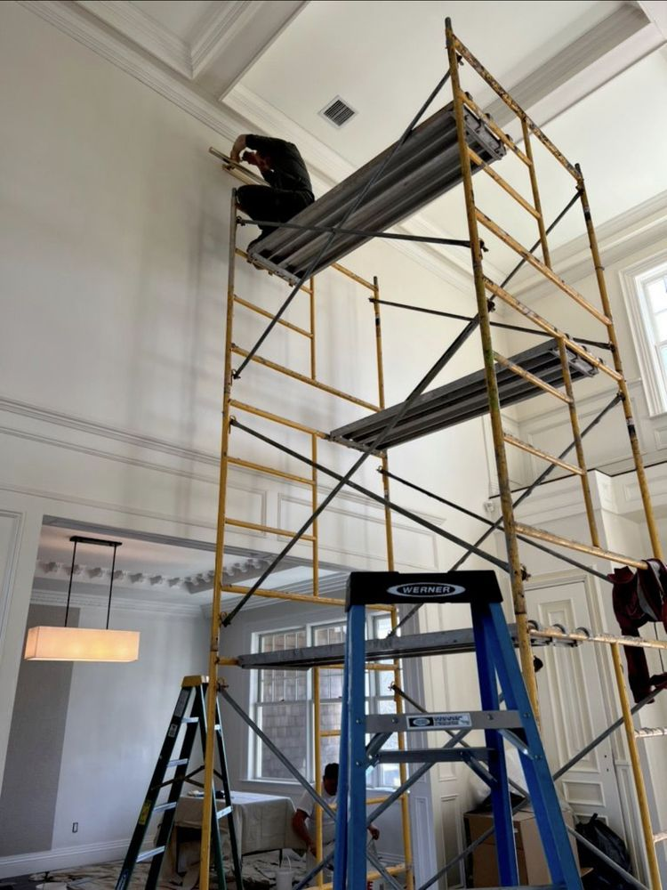 Tall scaffolding in a room with high ceilings. A person is working at the top.