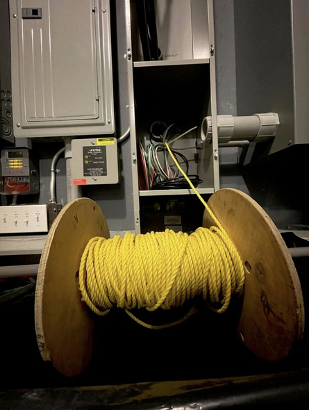 Yellow rope spool in front of electrical panel and wiring cabinet.
