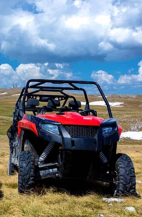 a red and black atv is parked on top of a grassy hill .