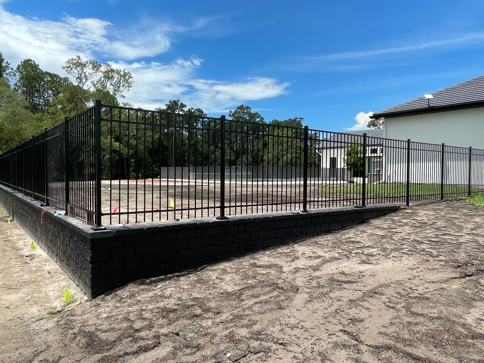 A concrete fence surrounds a lush green lawn.