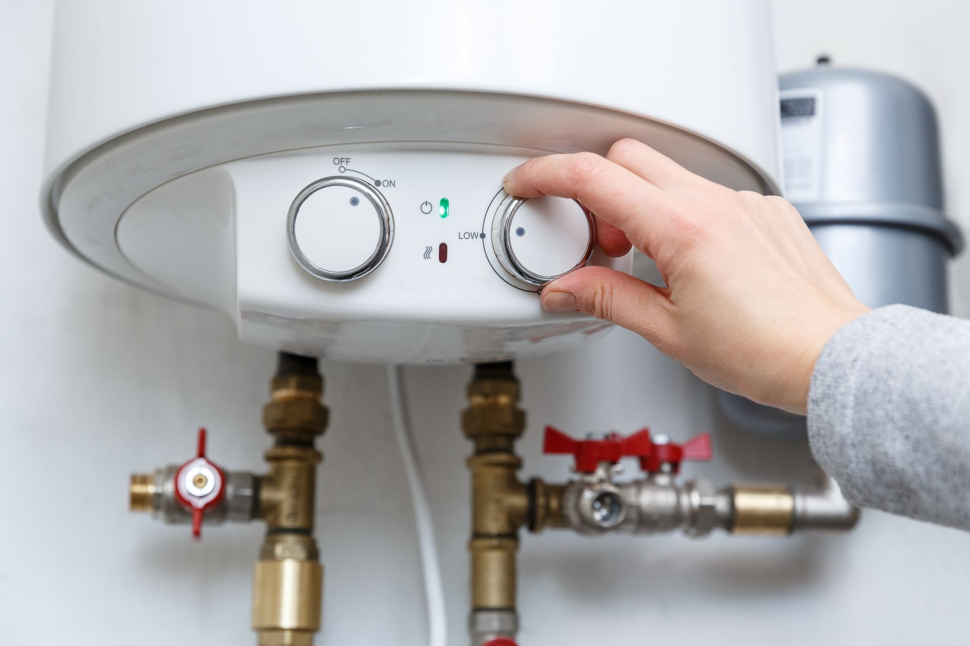 Hand Turning a Knob on A White Water Heater, Next to A Pressure — Leader Air Conditioning in Young, NSW
